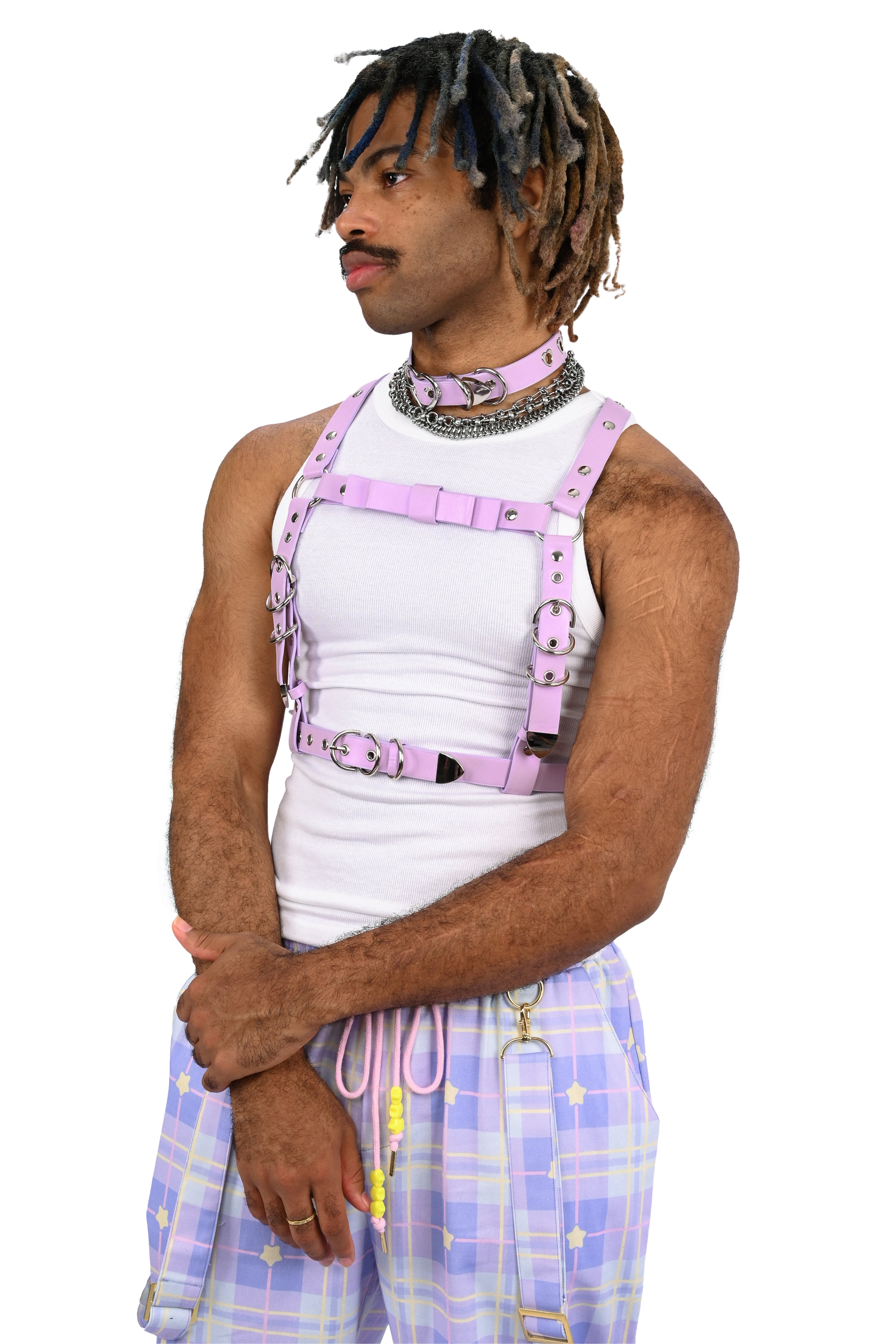 Person wearing a white tank top, pink harness, and plaid shorts on a white background