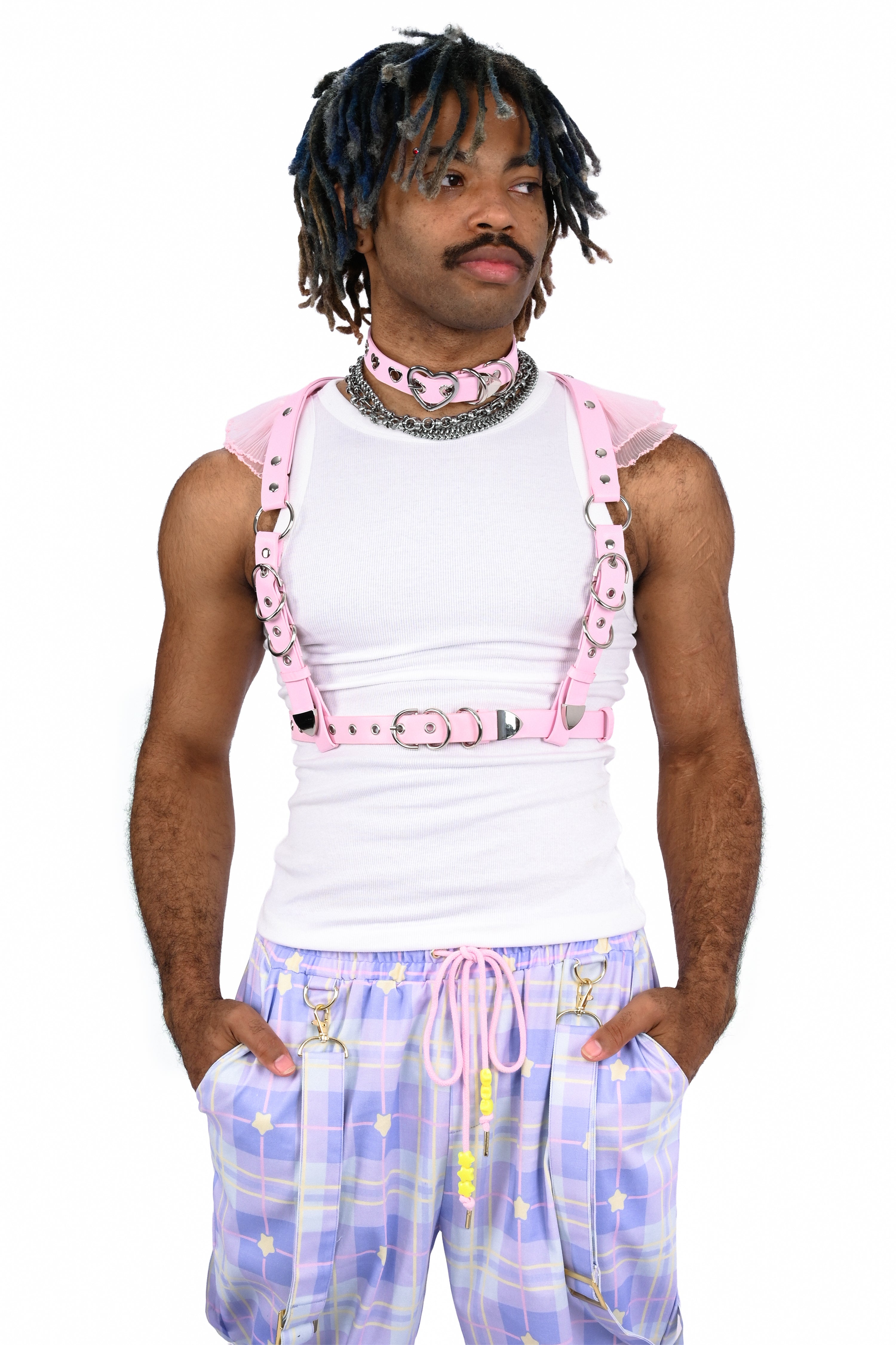Person wearing a white tank top, pink suspenders, and plaid pants on a white background