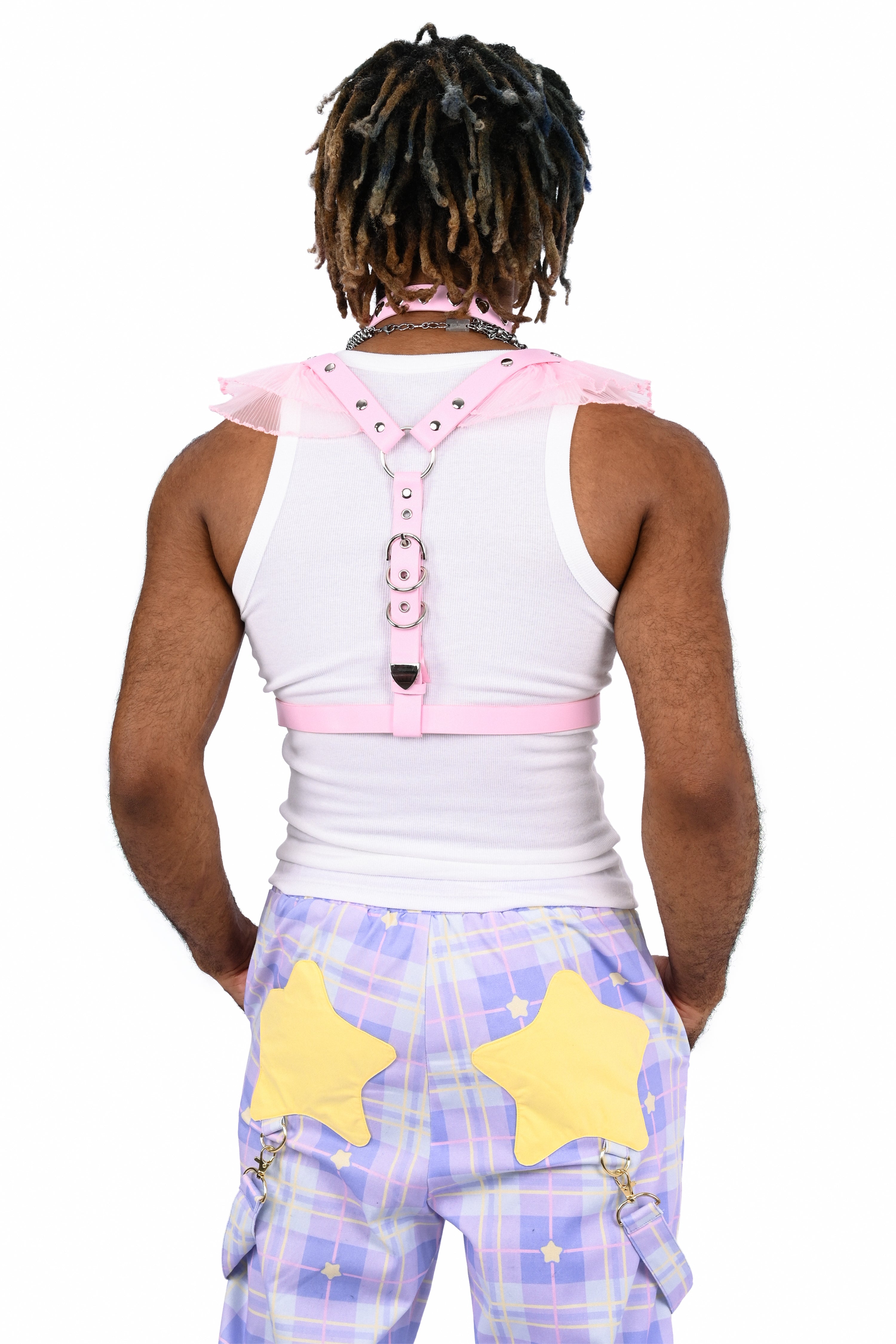 Person wearing a white sleeveless top with pink accents and purple pants with yellow stars on a white background