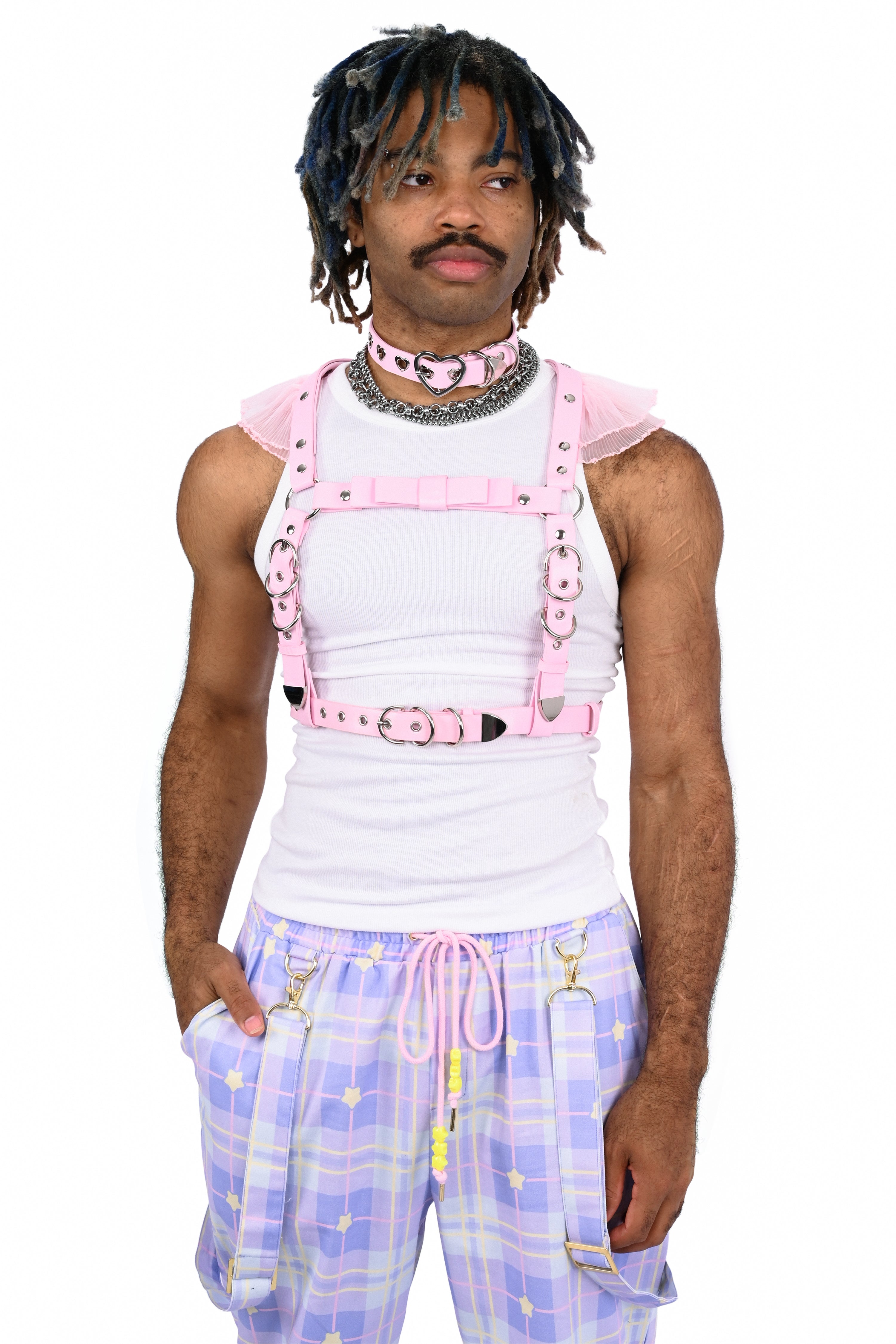 Person wearing a white tank top with pink suspenders and plaid pants on a white background