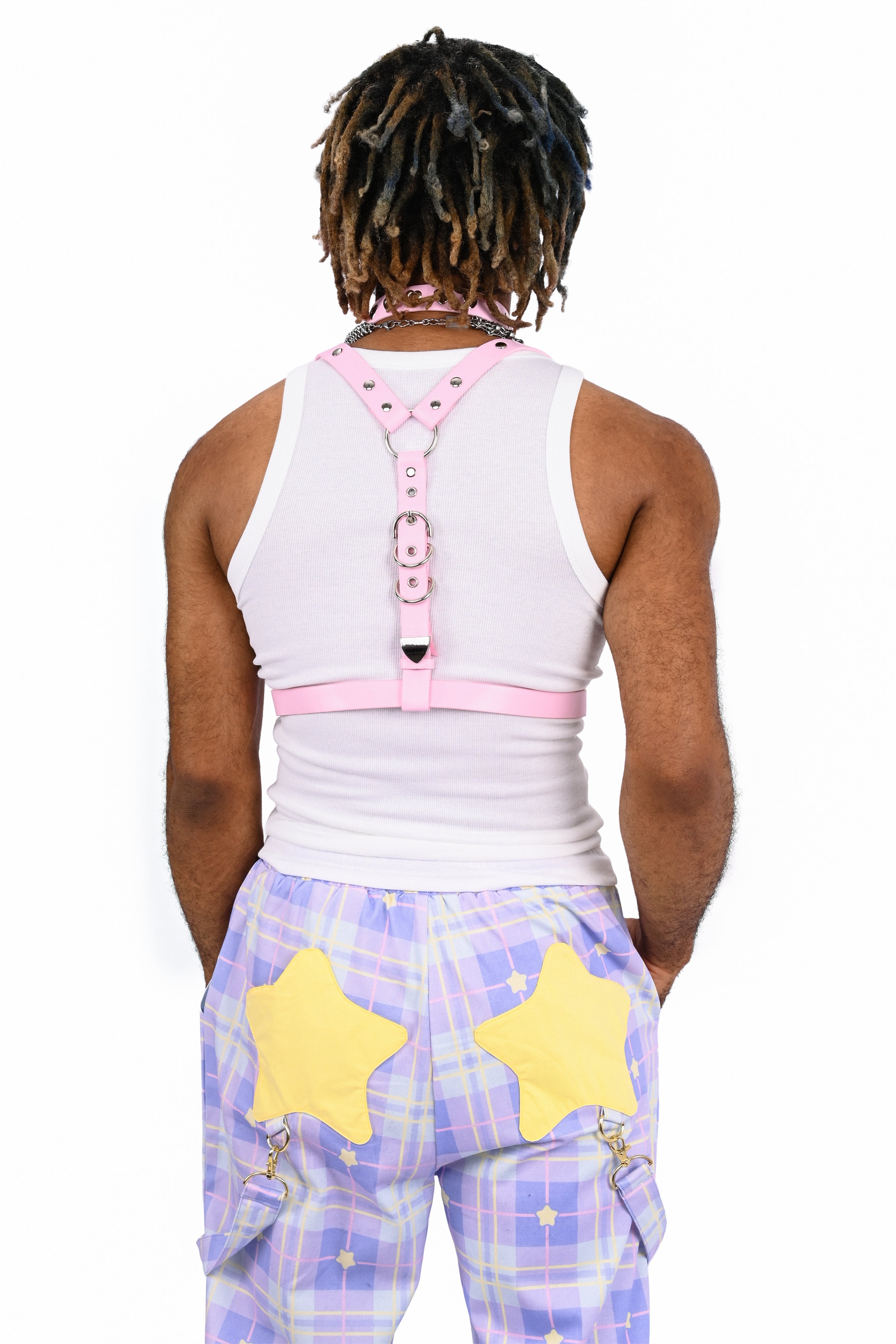 Person wearing a white sleeveless top with pink accents and purple plaid pants with yellow stars on a white background