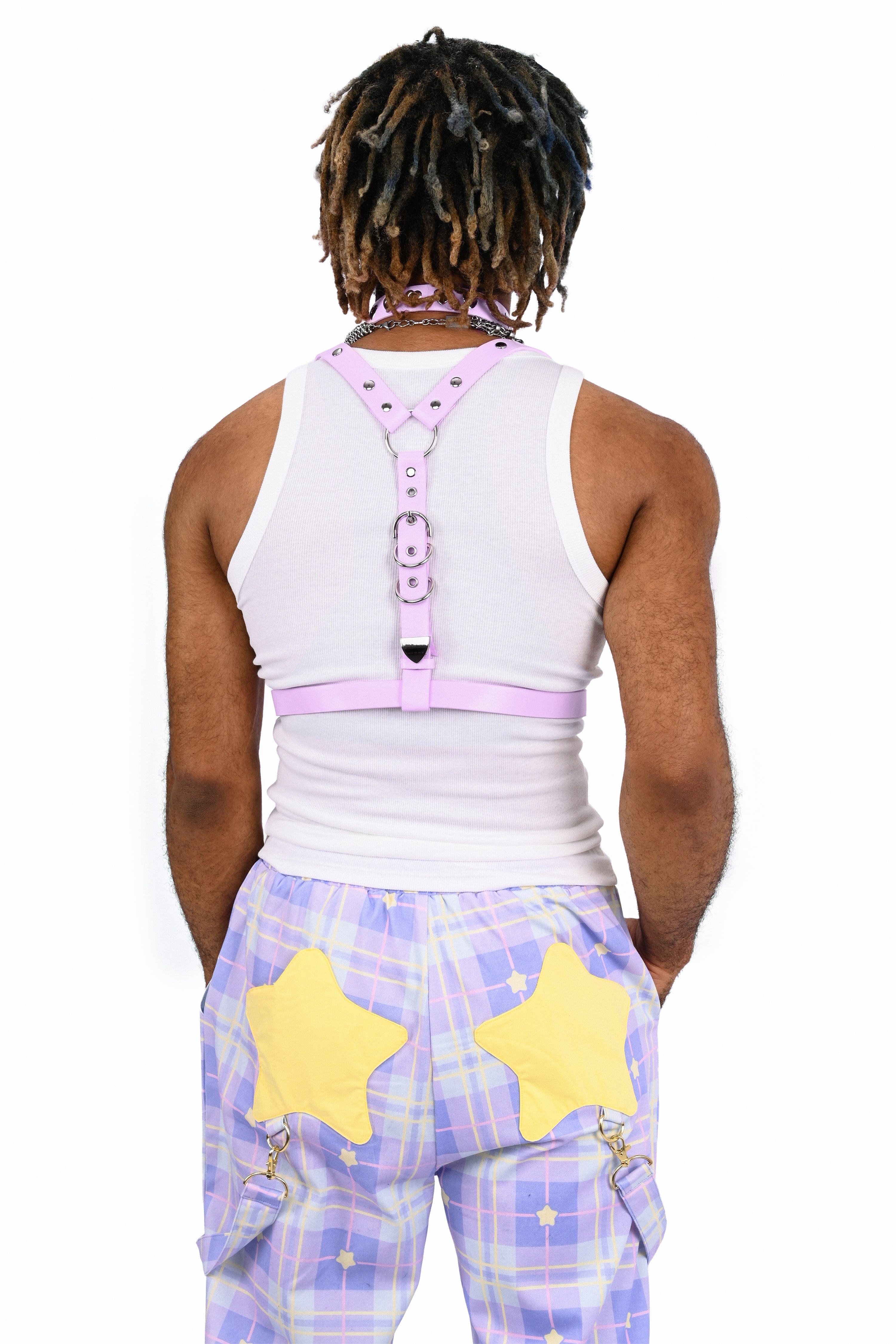 Person wearing a white sleeveless top with pink accents and purple plaid pants with yellow stars on a white background