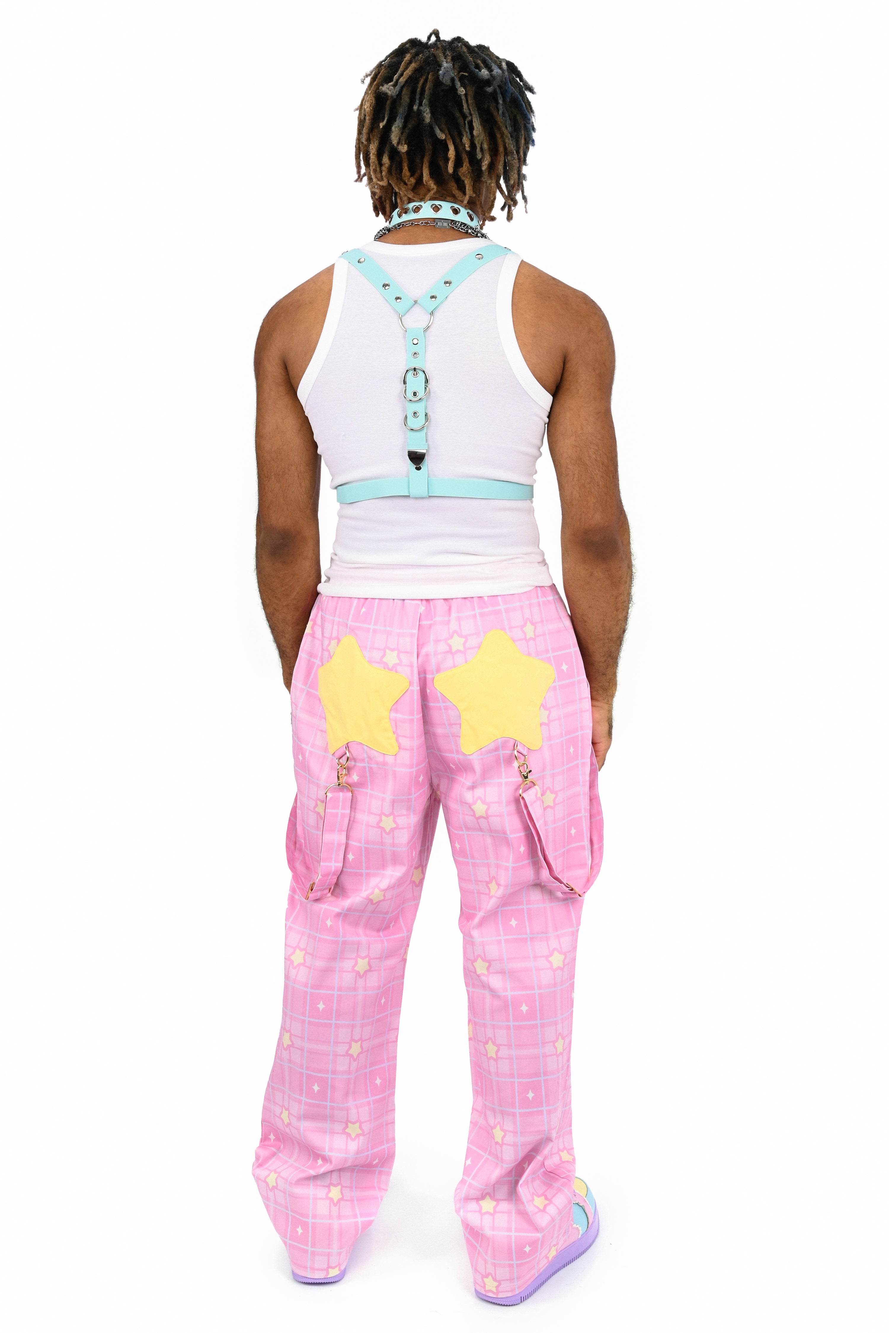 Person wearing a white tank top with blue straps and pink pants with yellow stars on a white background