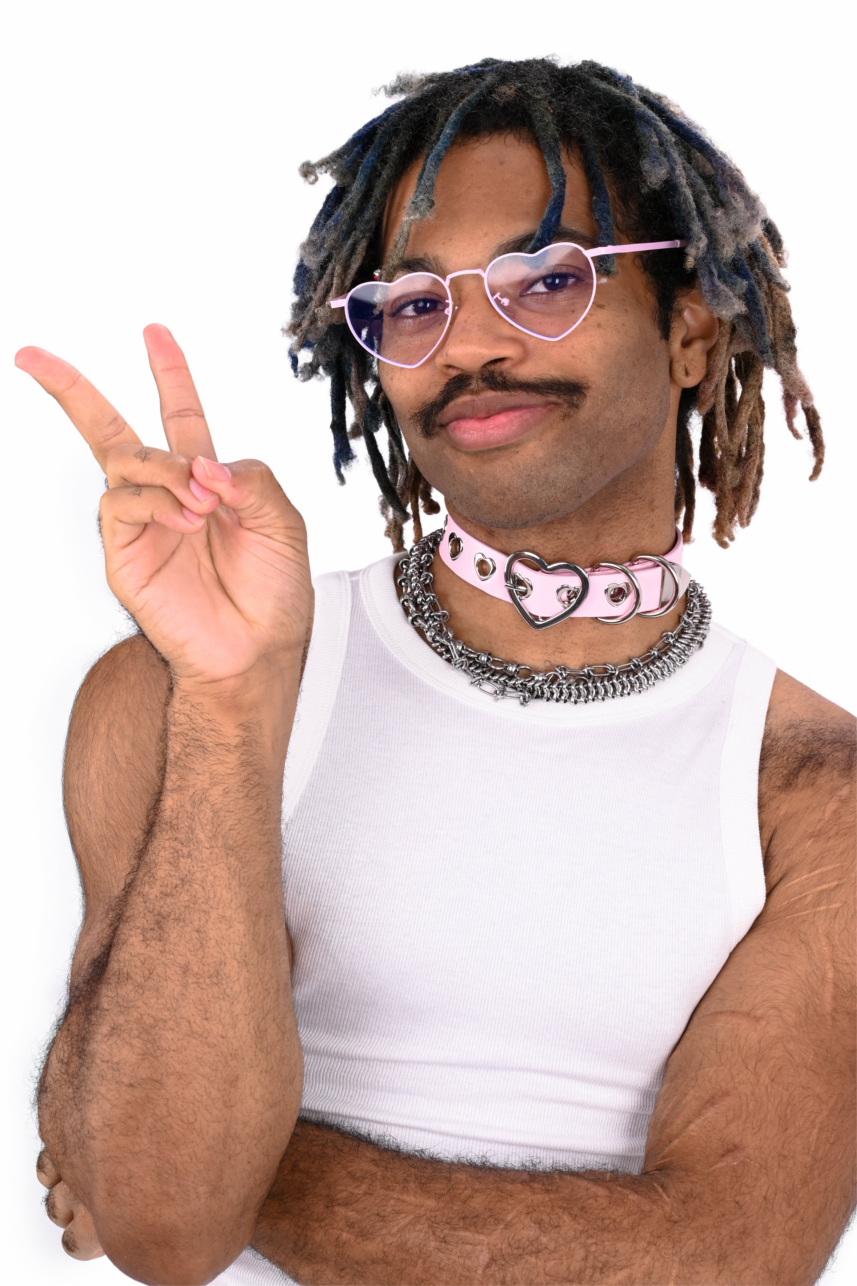 Person with dreadlocks and pink sunglasses making a peace sign on a white background