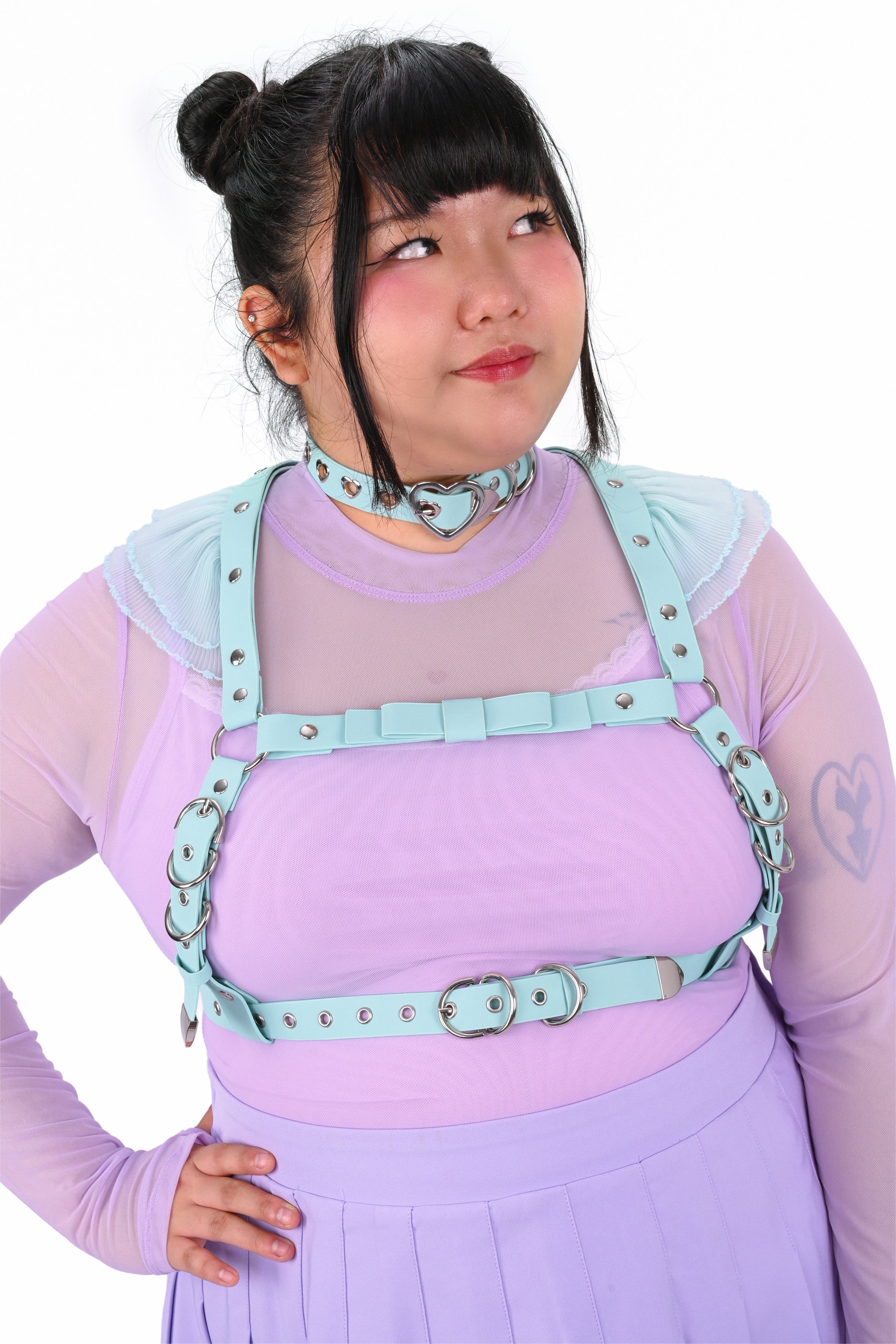 Person wearing a light purple outfit with teal straps and accessories on a white background