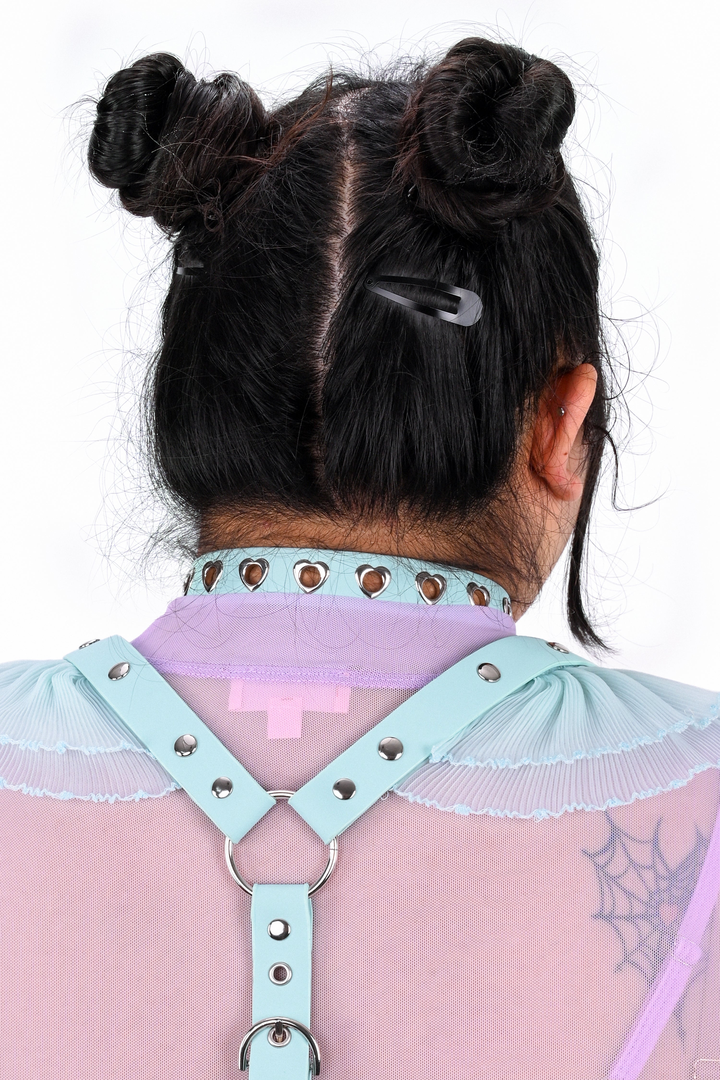 Person wearing a light blue harness with a pink top, back view
