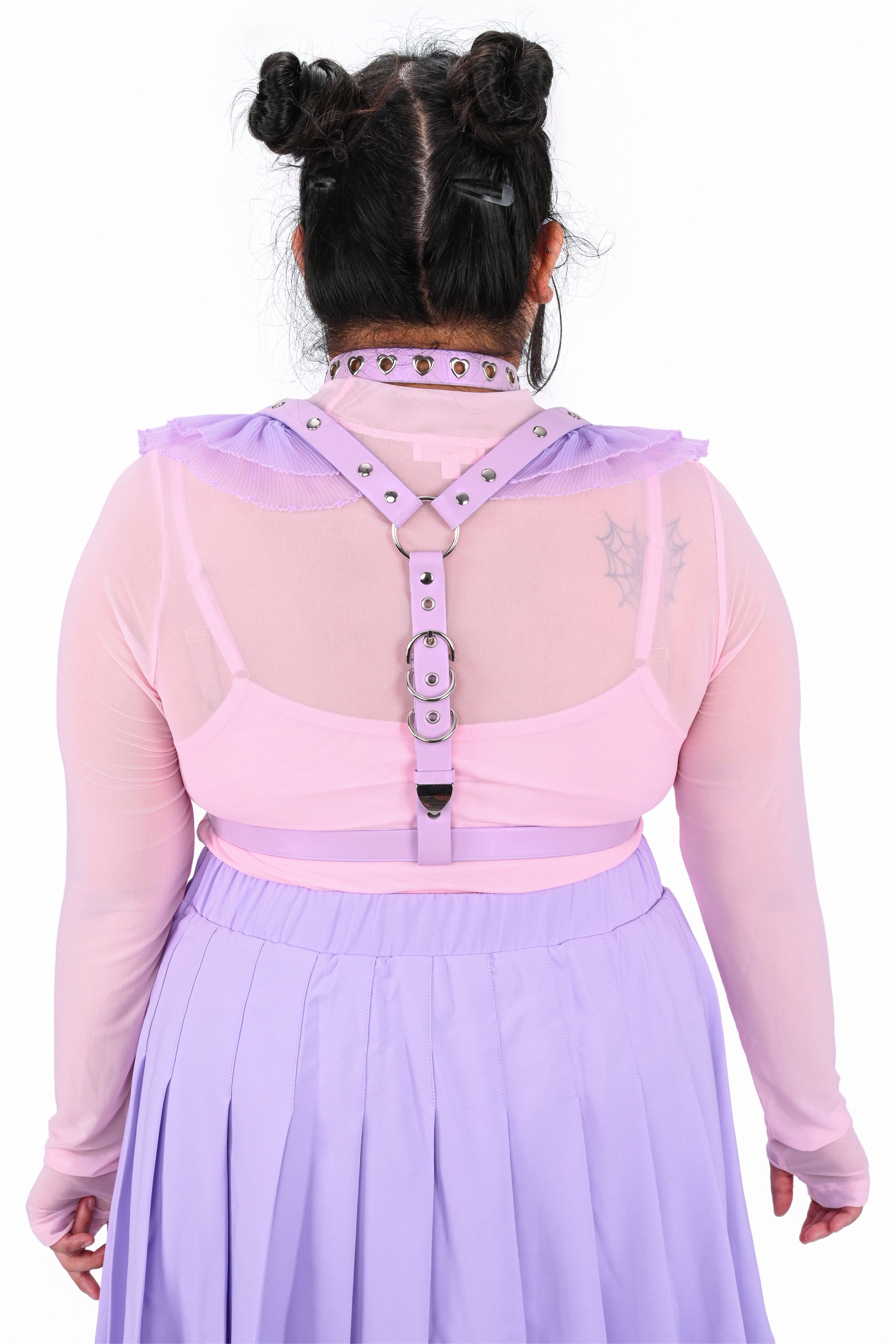 Person wearing a pink blouse with a harness and purple skirt on a white background
