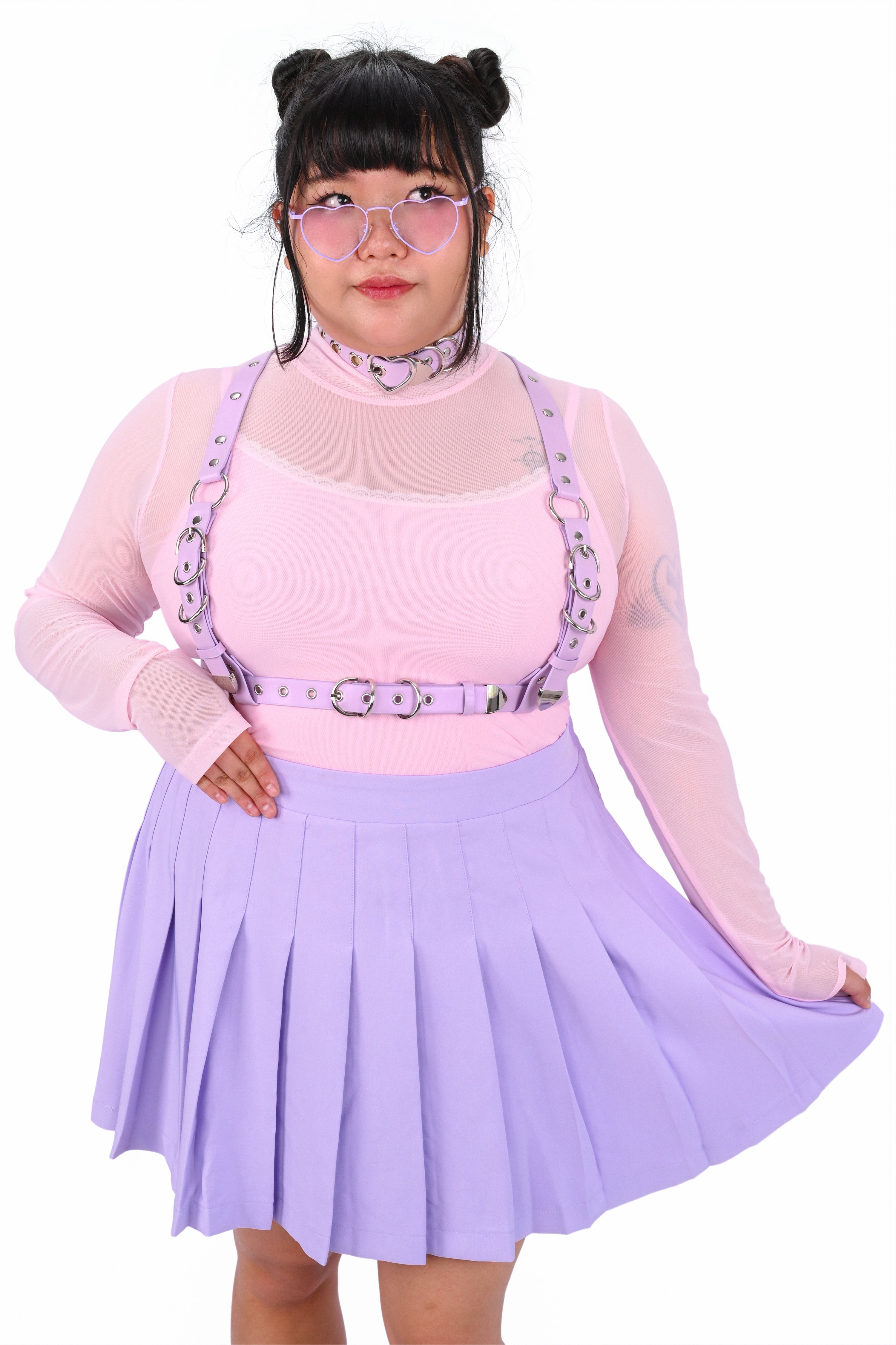 Person wearing a pink top, purple skirt, and suspenders on a white background