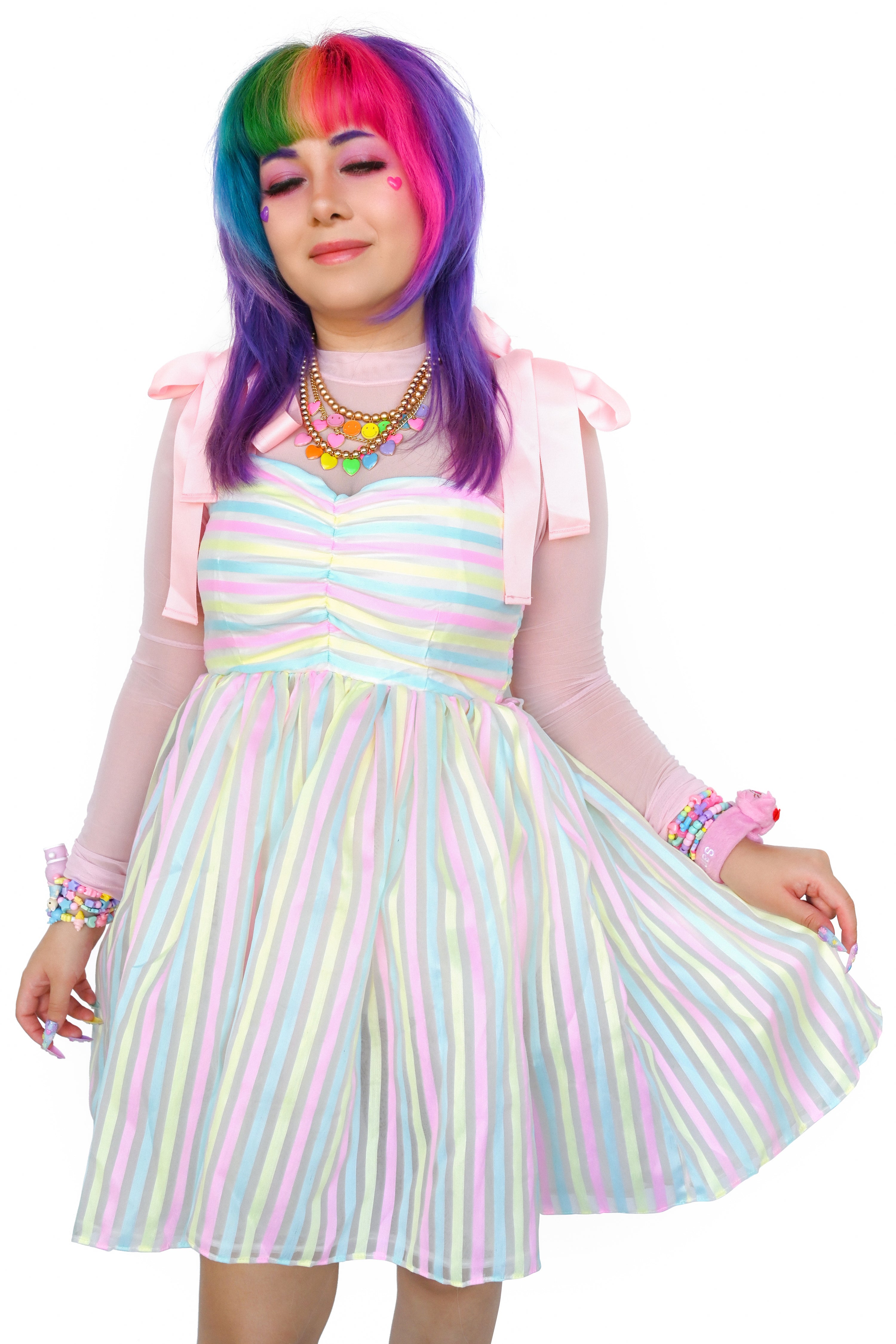 Pink ribbon straps, horizontal pastel yellow, blue, and pink stripes on the ruched bodice and a cupcake style sheer vertical striped skirt over a white slip