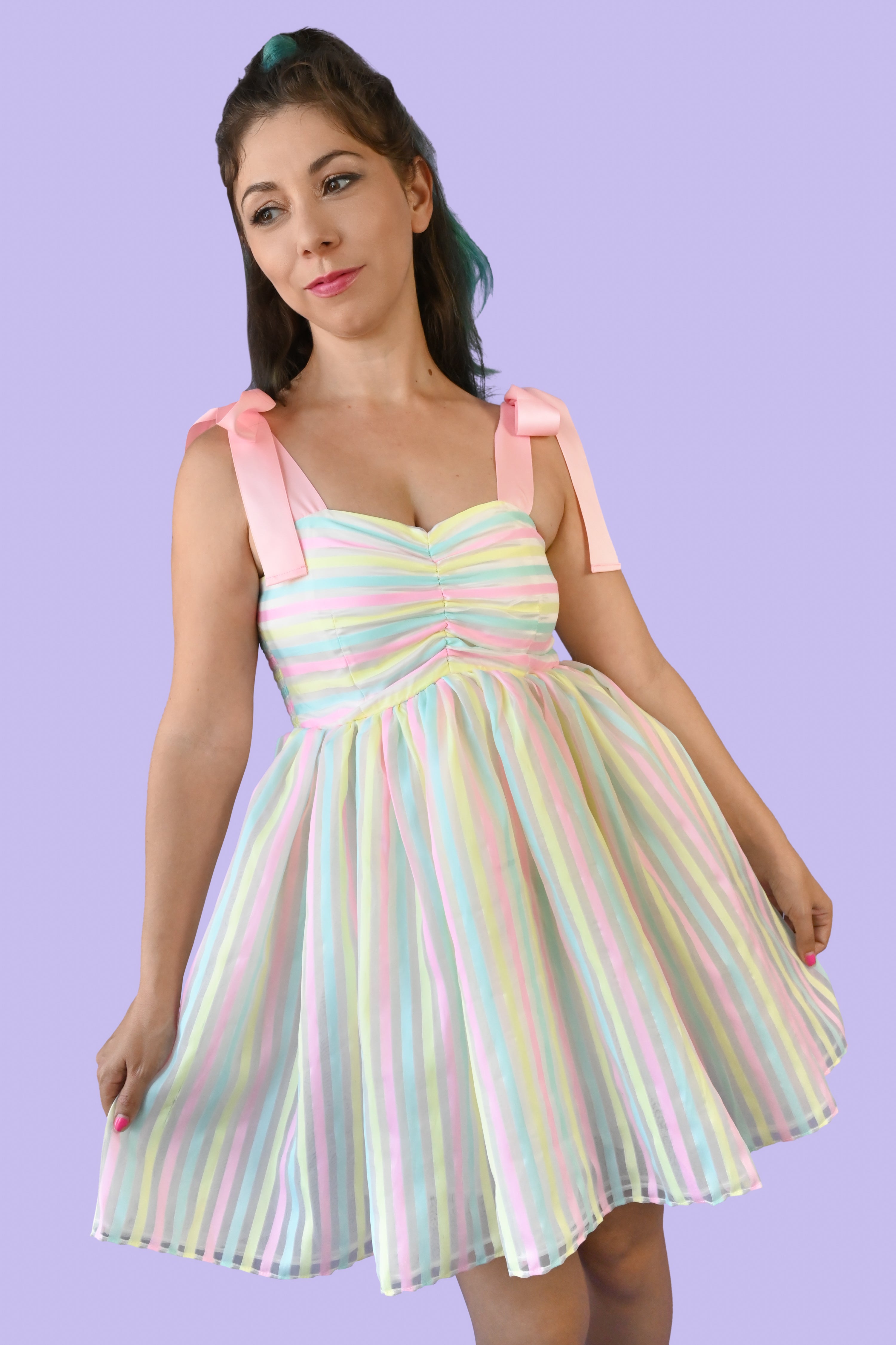 Pink ribbon straps, horizontal pastel yellow, blue, and pink stripes on the ruched bodice and a cupcake style sheer vertical striped skirt over a white slip