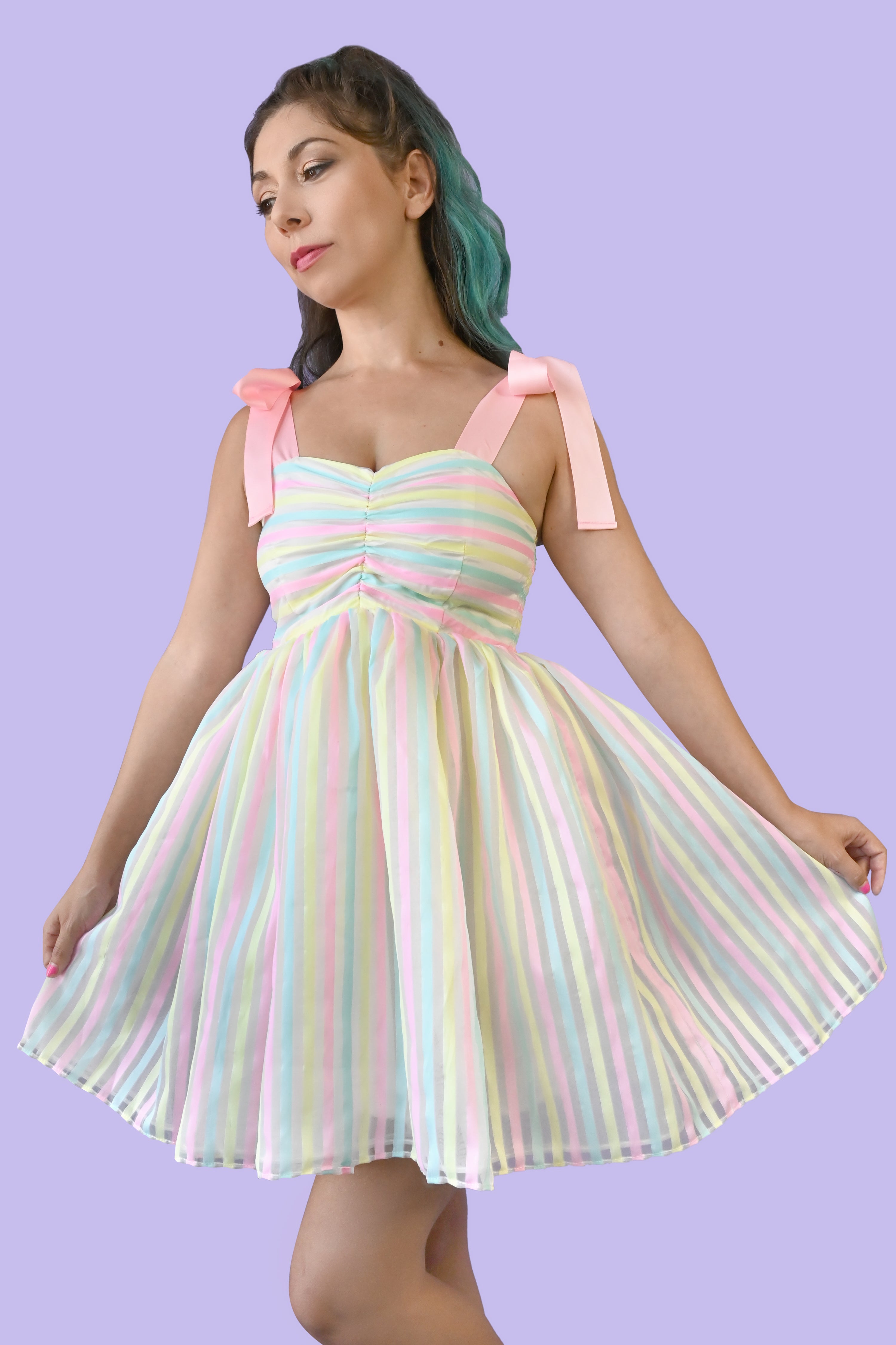 Pink ribbon straps, horizontal pastel yellow, blue, and pink stripes on the ruched bodice and a cupcake style sheer vertical striped skirt over a white slip