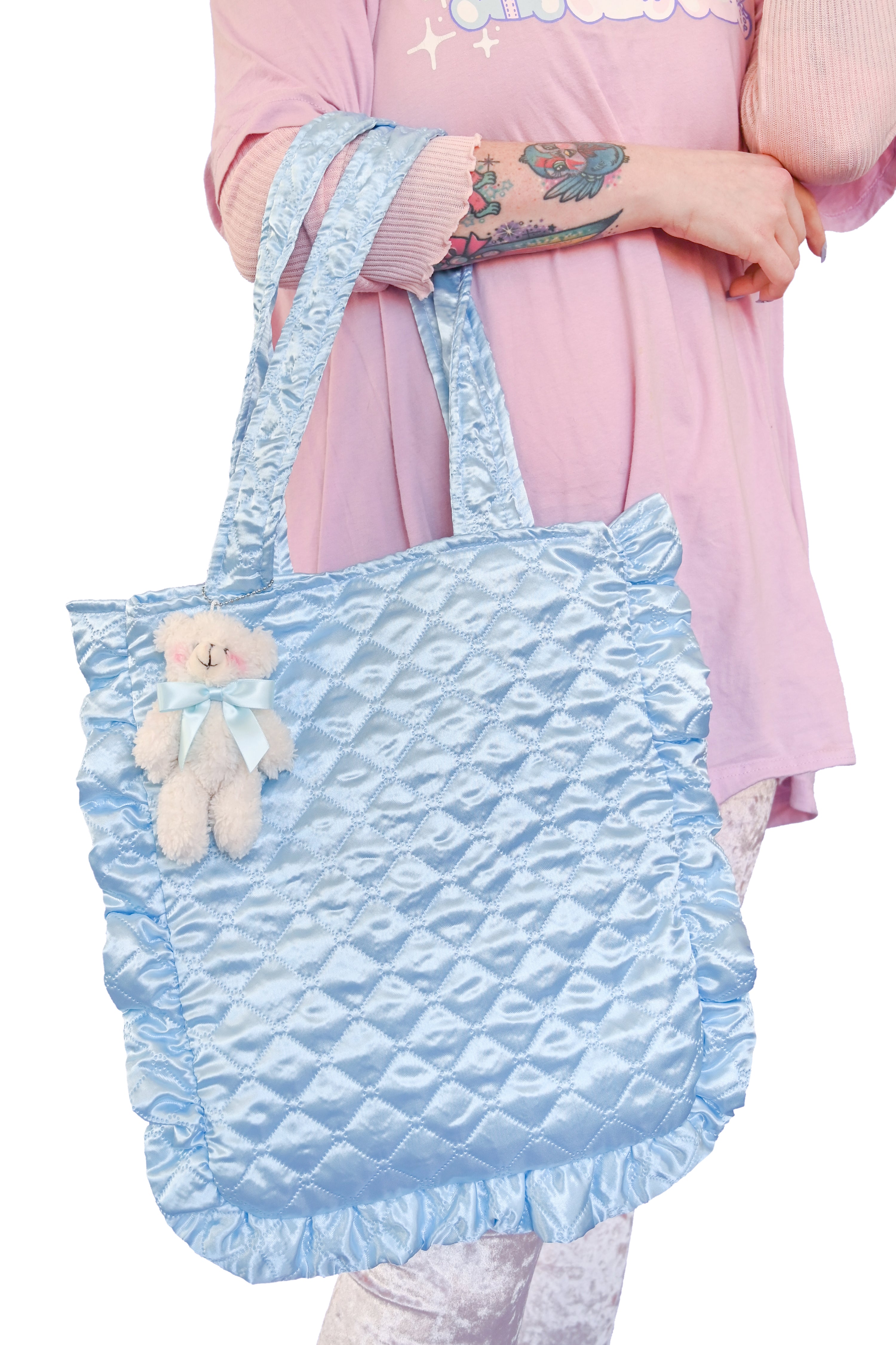 soft quilted blue satin tote bag with a chunky ruffled edge and a removable small white teddy bear with a blue ribbon bow tie
