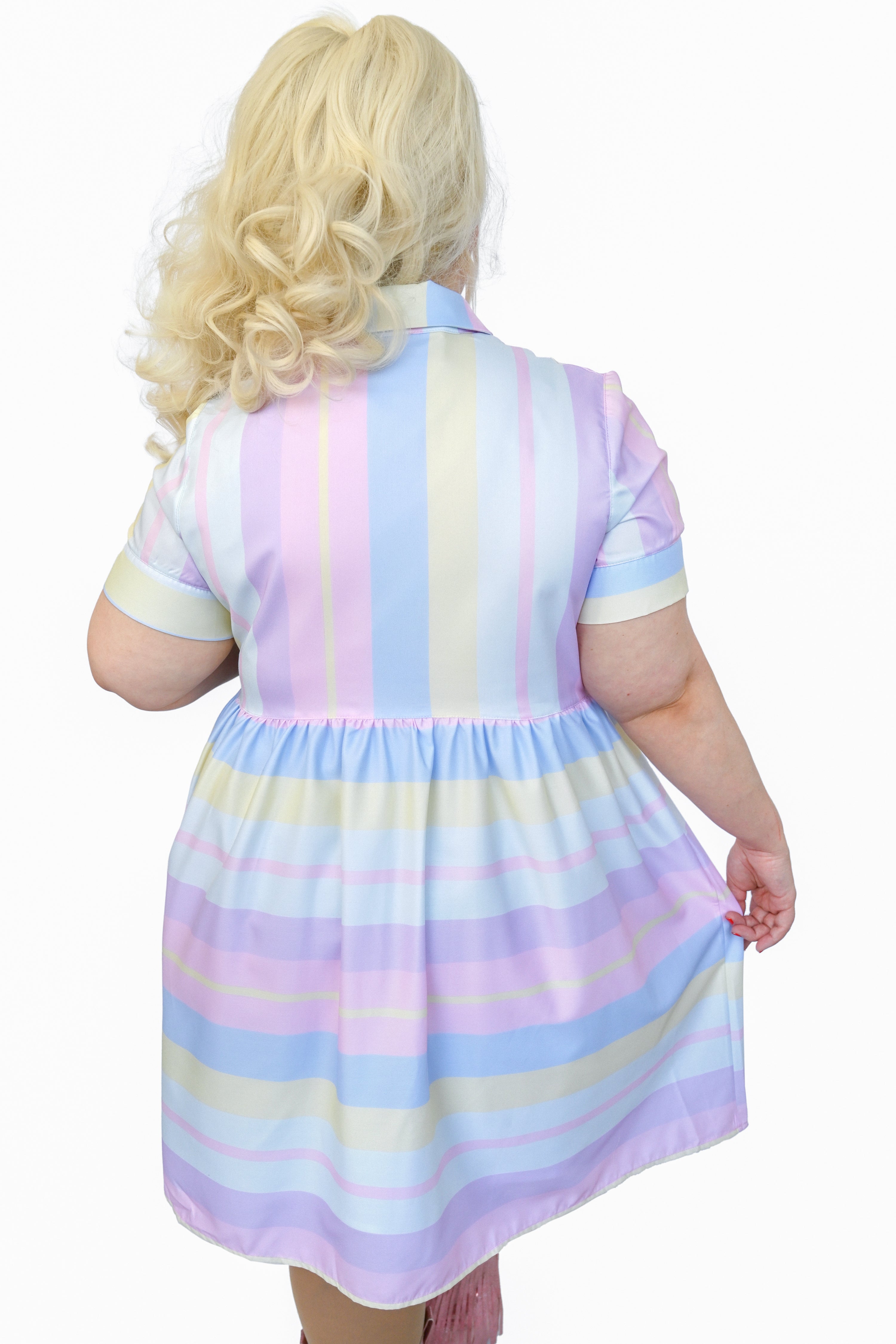 pastel striped button up dress with pointed collar, white flower buttons, and pink eyelet lace trim detail across the chest. Colours are: Pink, Purple, Light Blue, Yellow, Light Indigo. Vertical stripes on the top portion, horizontal on the lower half