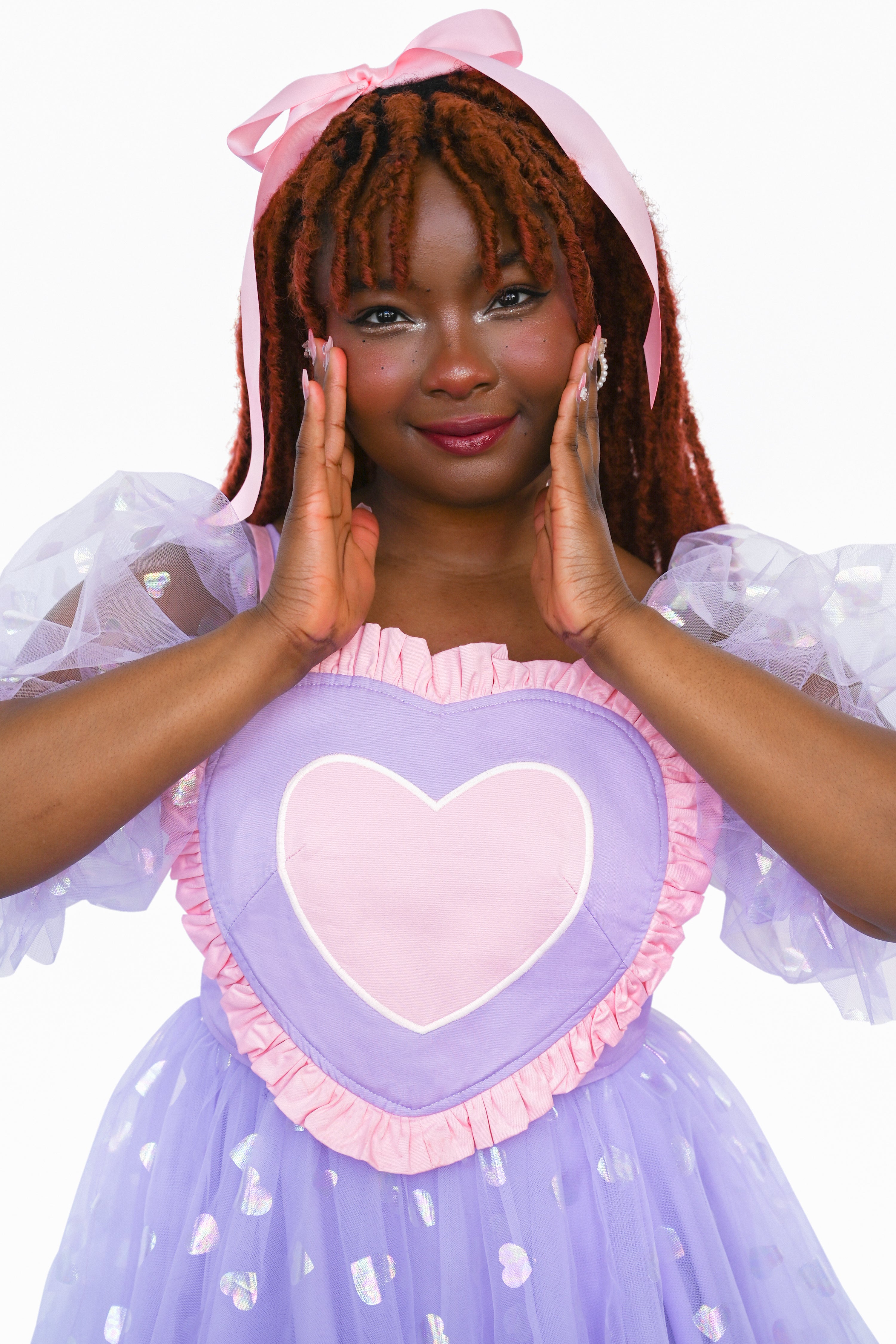 This pink, lavender, white, and light pink heart shaped corset top has adjustable straps and a lace-up back. The Base color of the corset top is lavender and a pink ruffle surrounds the other colours of the heart.