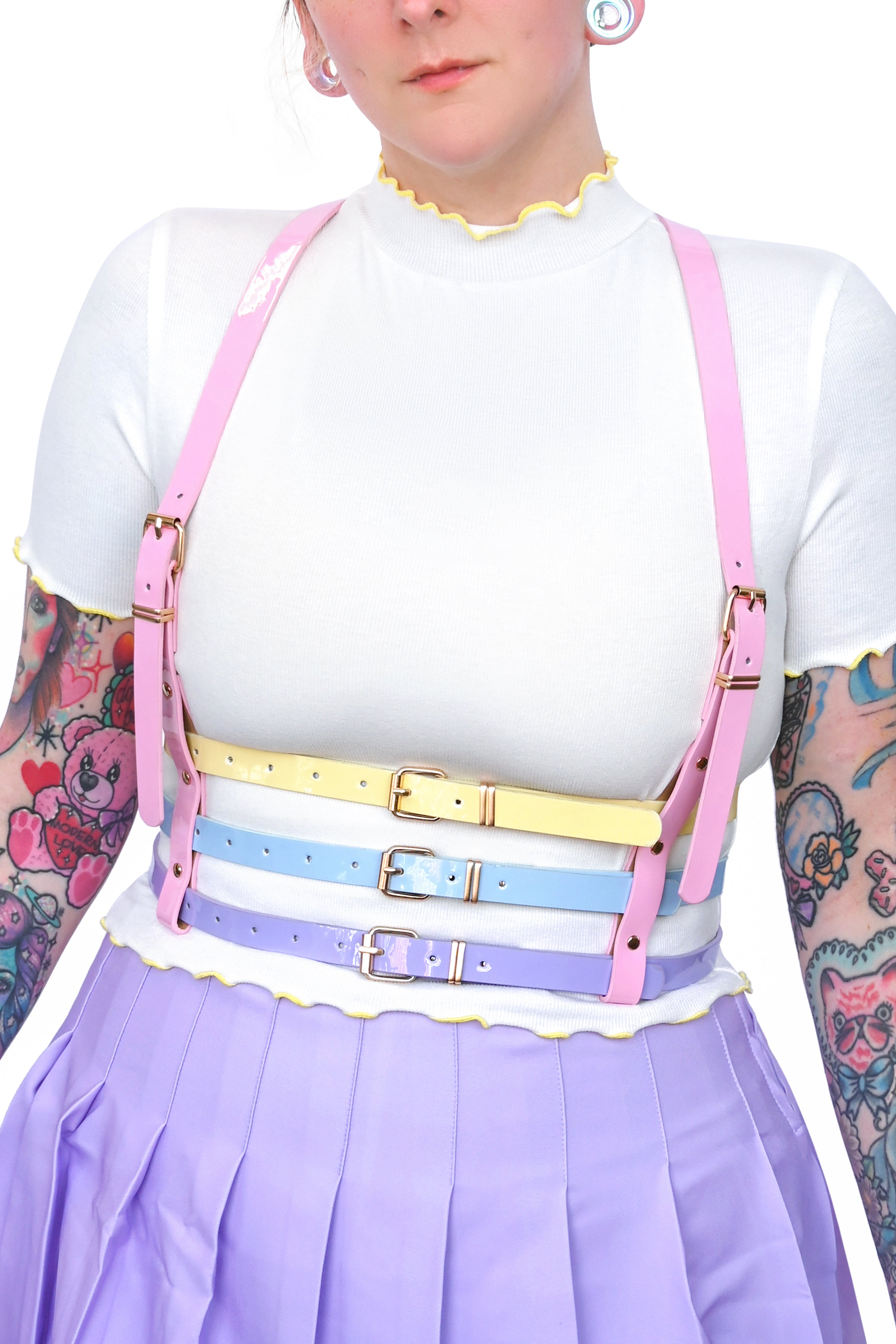 Model wearing a pink, yellow, blue, and purple harness with gold hardware