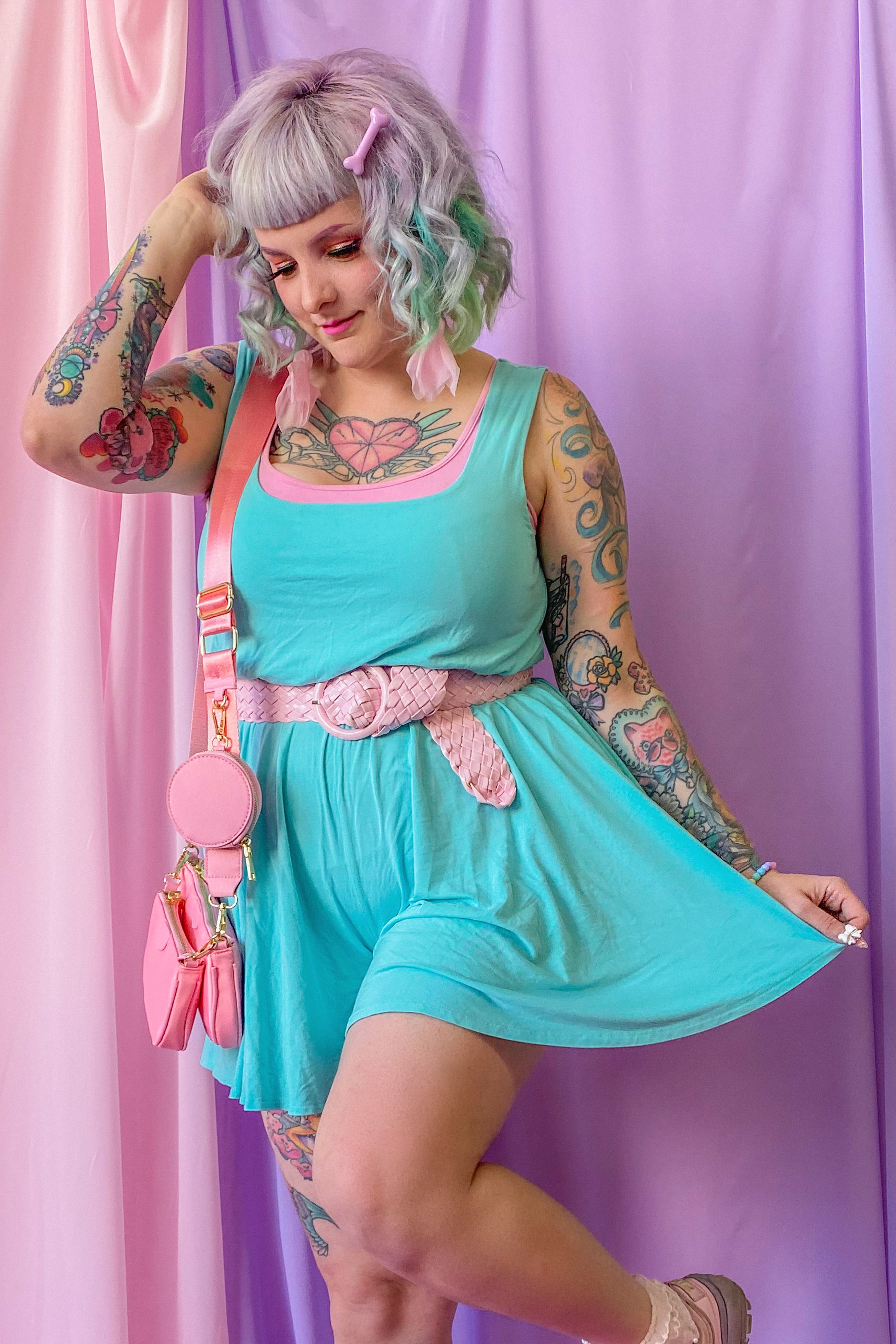 Model wearing mint Arielle romper, paired with a pink belt and bag